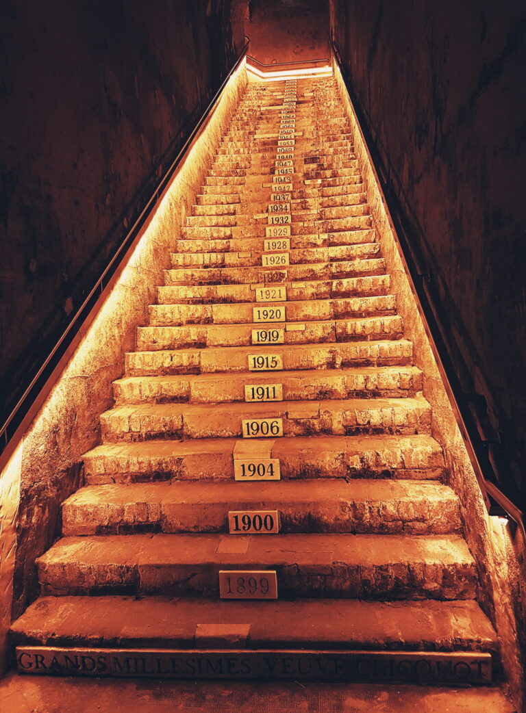 Weinkultur entdecken: Beleuchtete Treppe im Weinkeller von Veuve Clicquot mit Jahrgängen - Erleben Sie die Geschichte des Champagners mit Vinvac!